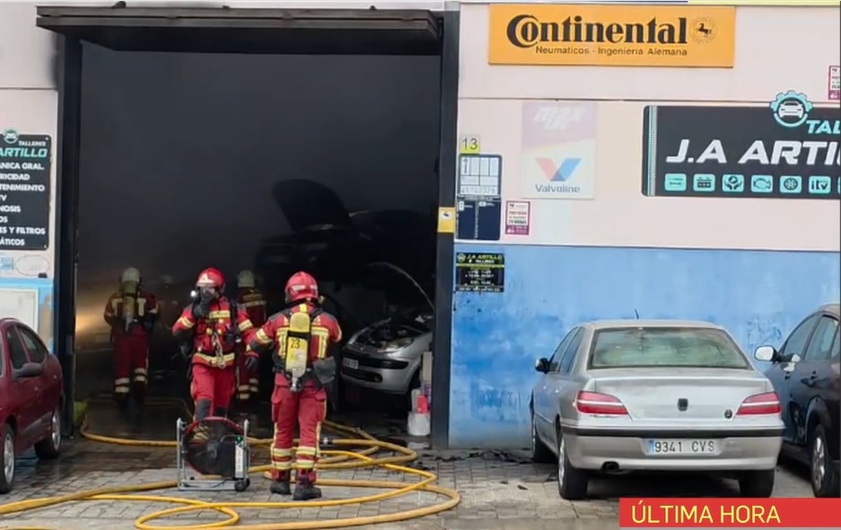 Un aparatoso incendio en un taller mecánico de Santiponce (Sevilla) calcina al menos cinco vehículos 
