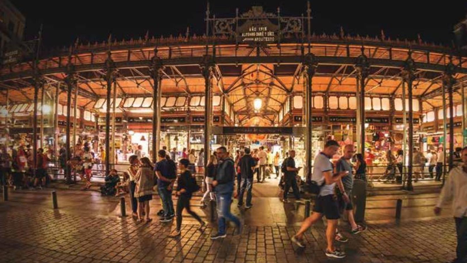 Varias personas caminan delante de un mercado municipal - 